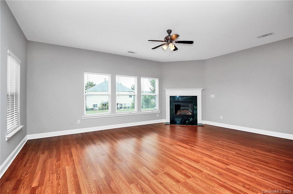 9522 Seamill Road Charlotte, NC 28278 - Photo 16 of 43 an empty room with wooden floor chandelier fan and windows