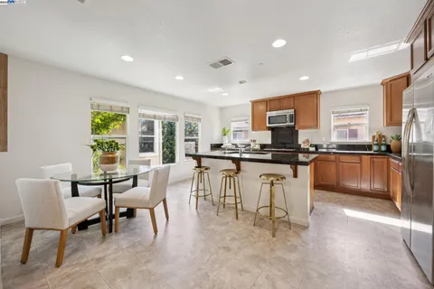 a kitchen with kitchen island granite countertop lots of white cabinets and stainless steel appliances