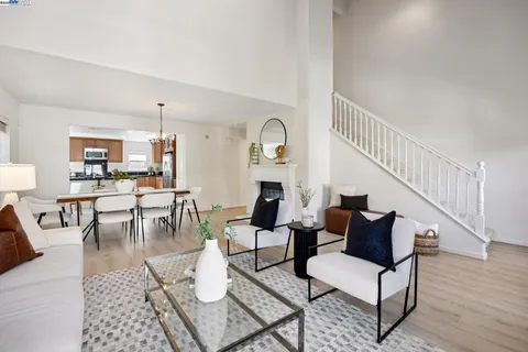 a living room with furniture and a dining table with wooden floor