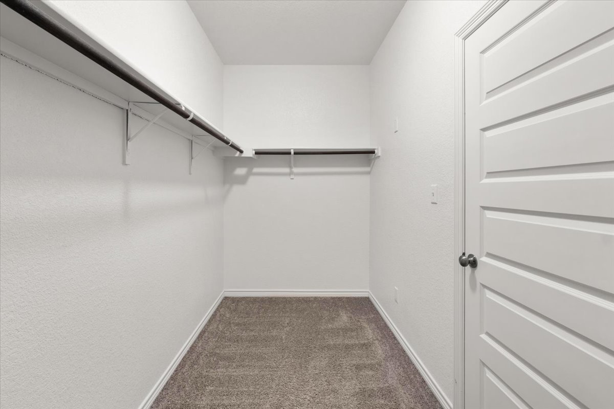 5408 Vanner Path Georgetown, TX 78626 - Photo 21 of 34 Spacious walk-in closet featuring plush carpeting, a multi-panel door with a matte black knob, and built-in shelving with hanging rods