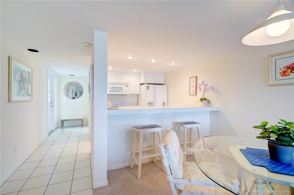 5593 Northeast Gulfstream Way Jensen Beach, FL 34957 - Photo 31 of 39 a kitchen with stainless steel appliances refrigerator dining table and chairs