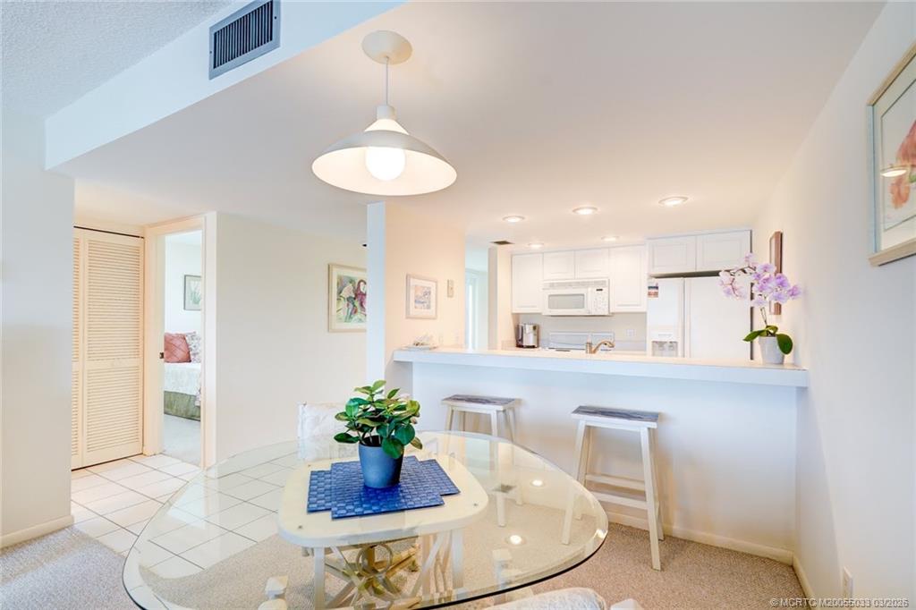 5593 Northeast Gulfstream Way Jensen Beach, FL 34957 - Photo 9 of 39 a kitchen with stainless steel appliances a dining table and chairs in it