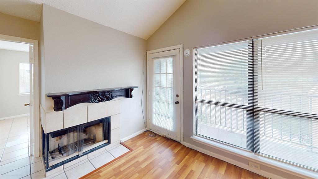 6108 Abrams Road, Unit 125 Dallas, TX 75231 - Photo 8 of 20 Vaulted ceiling, wood-finish flooring, fireplace with tile surround and ornate mantel, glass-panel door, and large window with blinds