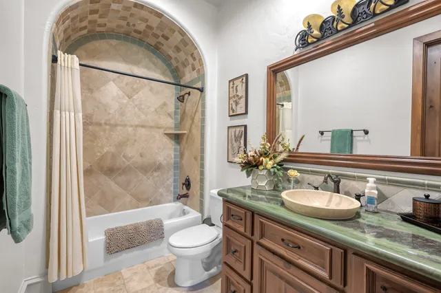 a bathroom with a granite countertop sink a toilet a mirror and shower