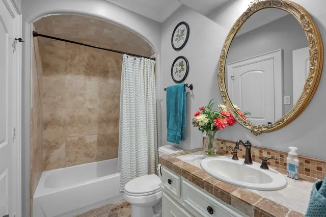 a bathroom with a granite countertop sink mirror toilet and bathtub