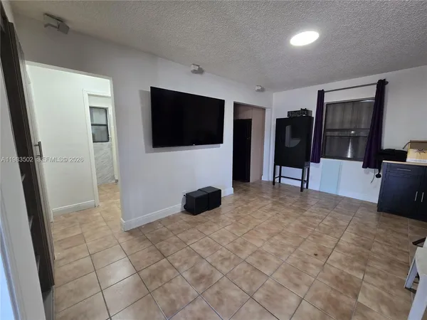 a view of a livingroom with entryway flat screen tv wooden shelves and closet