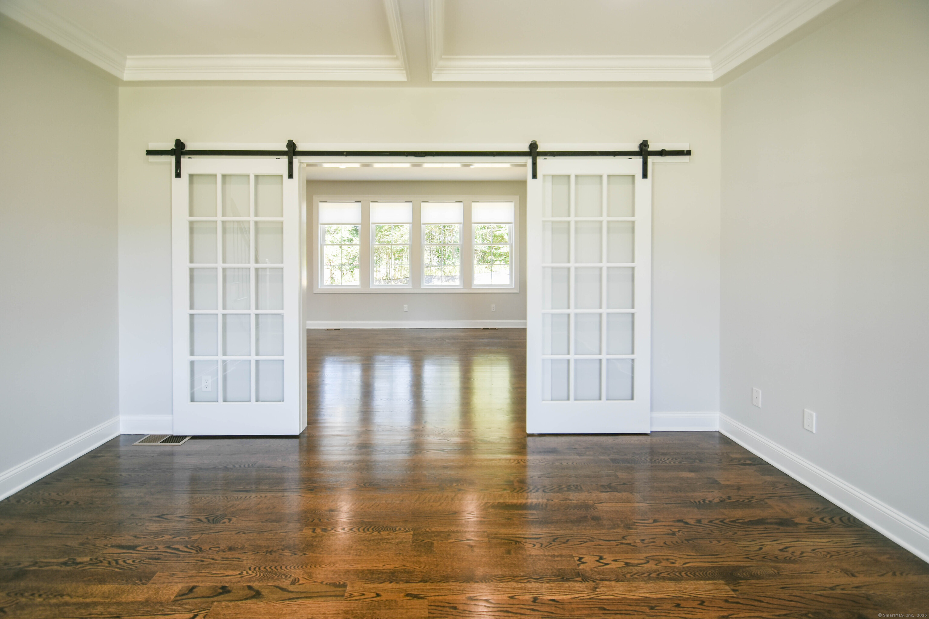 a view of empty room with wooden floor and fan