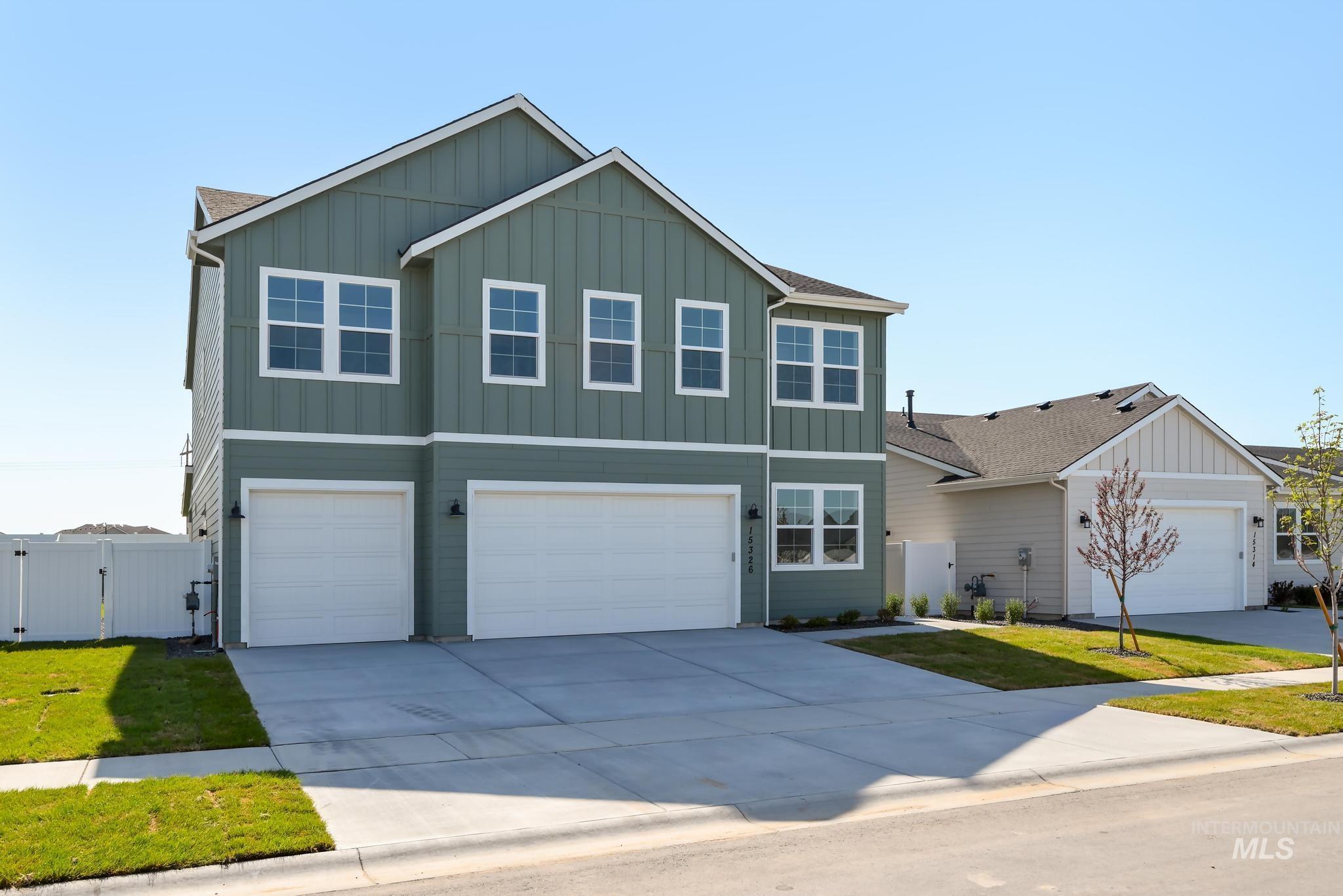 View of front facade featuring a gate, board and batten siding, an attached garage, driveway, and roof with shingles