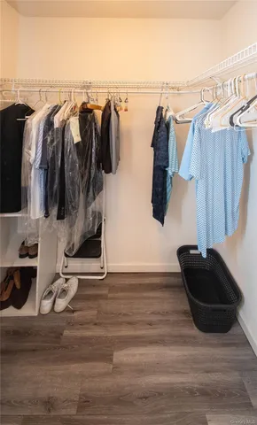 a walk in closet with wooden floor