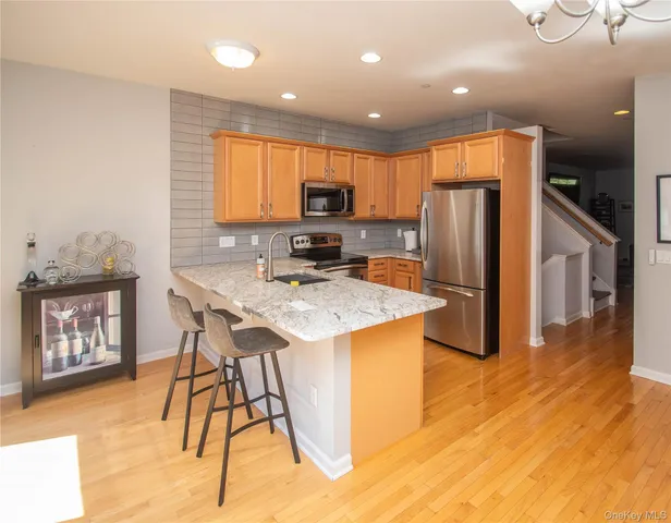 a kitchen with stainless steel appliances kitchen island granite countertop a refrigerator a stove a microwave oven with a dining table and chairs