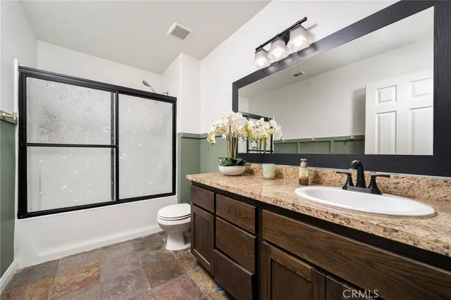 a bathroom with a granite countertop sink toilet and mirror