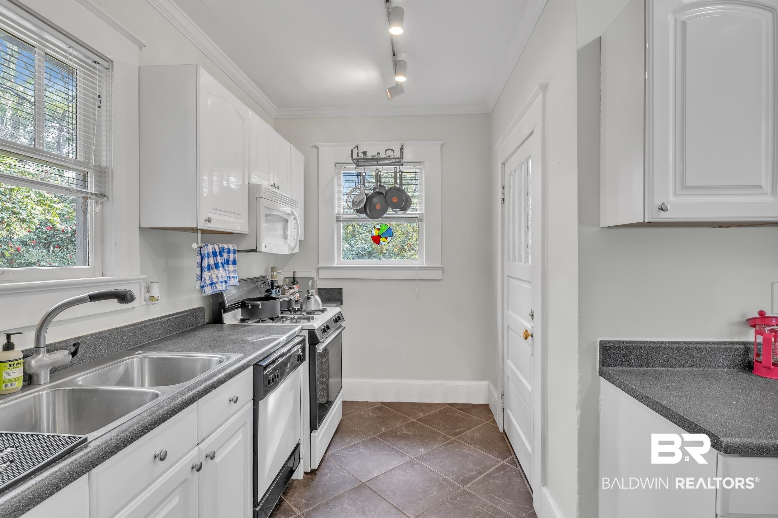 55 Mohawk Street Mobile, AL 36606 - Photo 25 of 28 Kitchen featuring a sink, white cabinets, crown molding, dishwashing machine, and white microwave