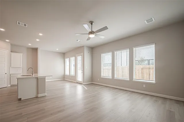 a view of an empty room with window and wooden floor