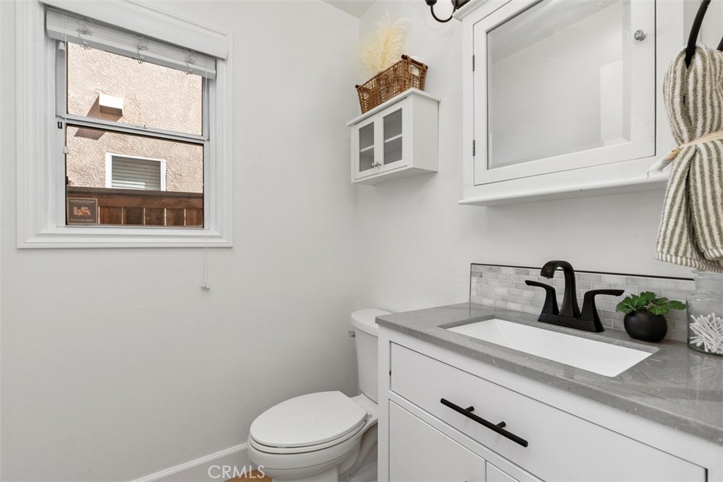 56 Acorn Ridge Rancho Santa Margarita, CA 92688 - Photo 37 of 57 Powder Room: Compact half bath with a white vanity, gray countertop, black fixtures, wall cabinet, and a window for added natural light.