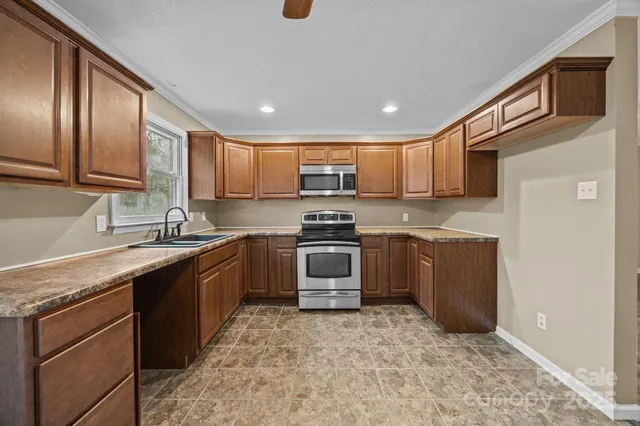 a kitchen with granite countertop a sink cabinets and stainless steel appliances