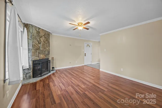 a view of empty room with fireplace and wooden floor