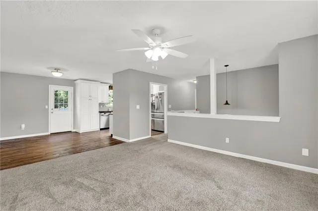 an empty room with a ceiling fan and windows