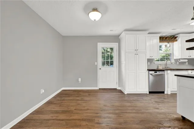 a kitchen with granite countertop a refrigerator and wooden floor