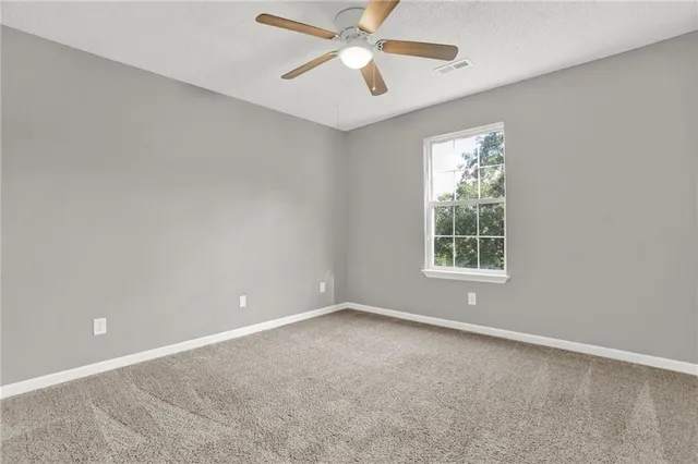 a view of an empty room and chandelier fan