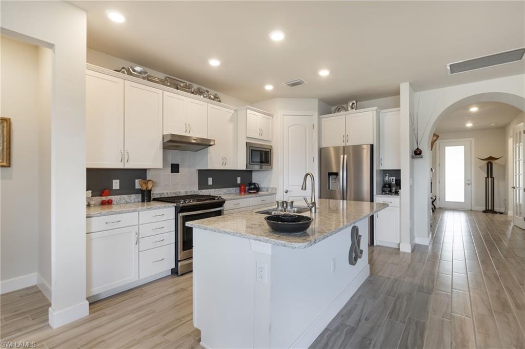 43007 Parkside Court Punta Gorda, FL 33982 - Photo 10 of 44 a kitchen with white cabinets and stainless steel appliances