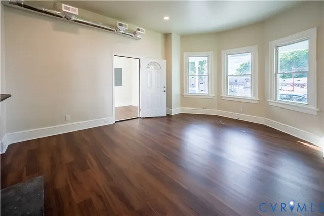 an empty room with wooden floor and windows