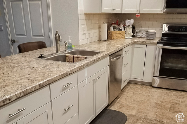 2855 South 1000 West Perry, UT 84302 - Photo 67 of 142 Kitchen with white cabinets, light countertops, stainless steel appliances, decorative backsplash, and a textured wall