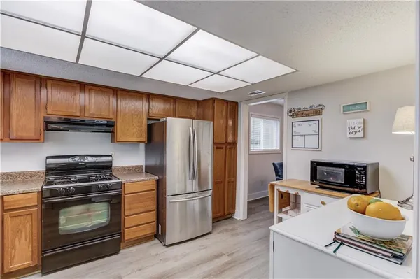 a kitchen with kitchen island granite countertop stainless steel appliances a stove refrigerator and a sink