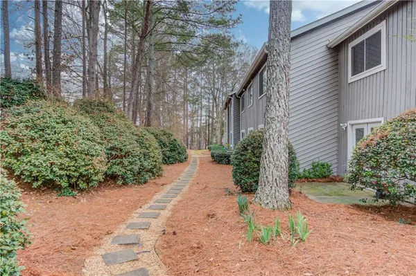 a pathway of a house with potted plants and large trees