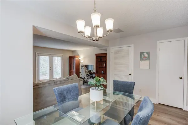 a dining room with wooden floor a chandelier a glass table and chairs