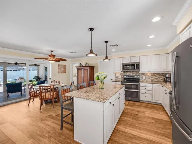 a kitchen with stainless steel appliances kitchen island granite countertop a table chairs stove and refrigerator