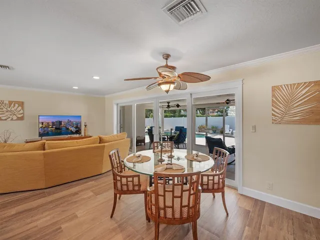 a dining room with furniture a kitchen a chandelier and wooden floor