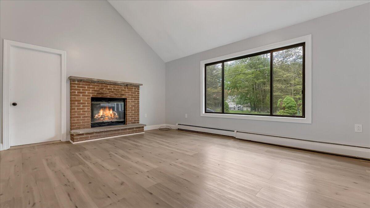 7198 Rimrock Drive Tobyhanna, PA 18466 - Photo 7 of 38 an empty room with wooden floor fireplace and windows