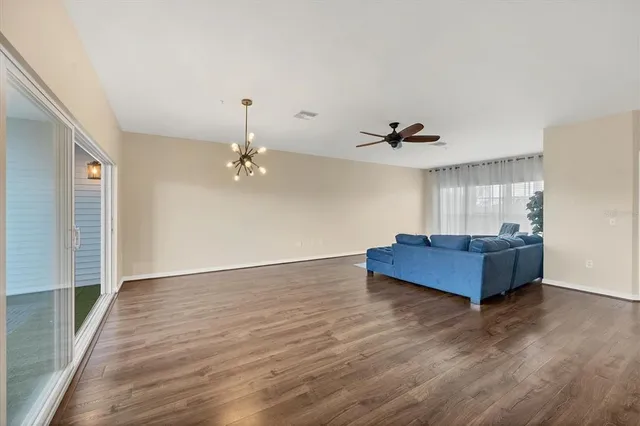an empty room with wooden floor ceiling fan and windows