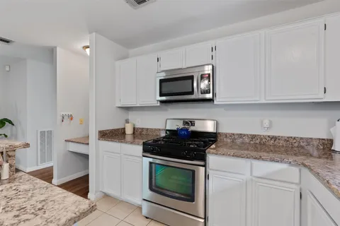 a kitchen with stainless steel appliances granite countertop white cabinets granite counter tops and a stove