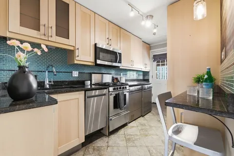 a kitchen with stainless steel appliances granite countertop a sink a stove top oven a counter space and cabinets