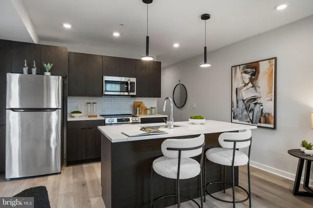 a kitchen with a refrigerator a stove a dining table and chairs with wooden floor