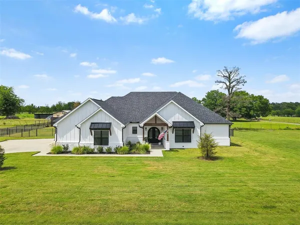 a front view of a house with a garden and lake view