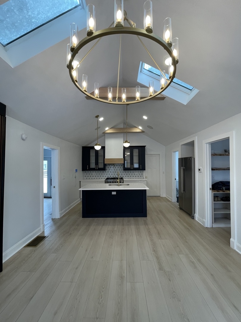 607 West Olive Street Bloomington, IL 61701 - Photo 3 of 17 an empty room with wooden floor chandelier and kitchen view