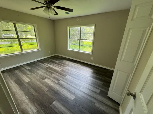 a view of an empty room with a window and wooden floor