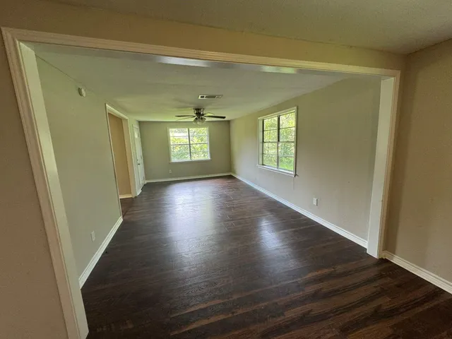 an empty room with wooden floor and windows