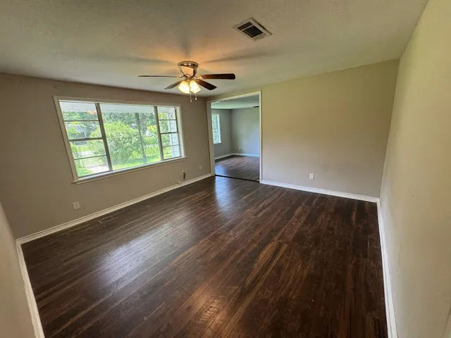 a view of an empty room with wooden floor and a window