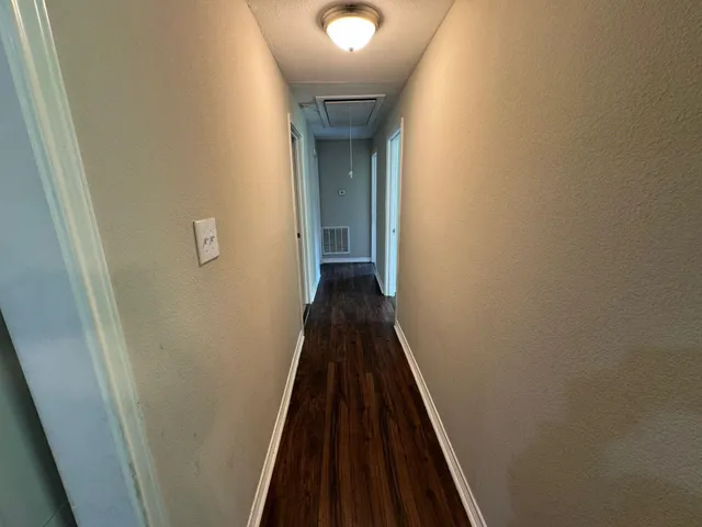 a view of a hallway with wooden floor and a staircase