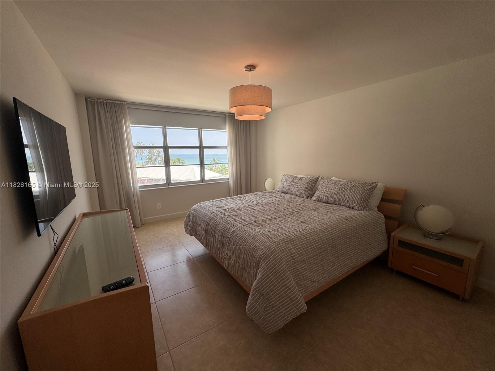 5151 Collins Avenue, Unit 535 Miami Beach, FL 33140 - Photo 12 of 34 a bedroom with a bed and a flat screen tv