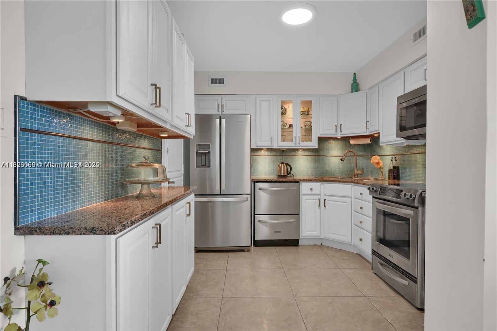 5151 Collins Avenue, Unit 535 Miami Beach, FL 33140 - Photo 10 of 34 a kitchen with white cabinets and appliances