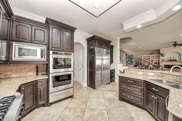 a kitchen with stainless steel appliances kitchen island granite countertop a dining table chairs and a refrigerator