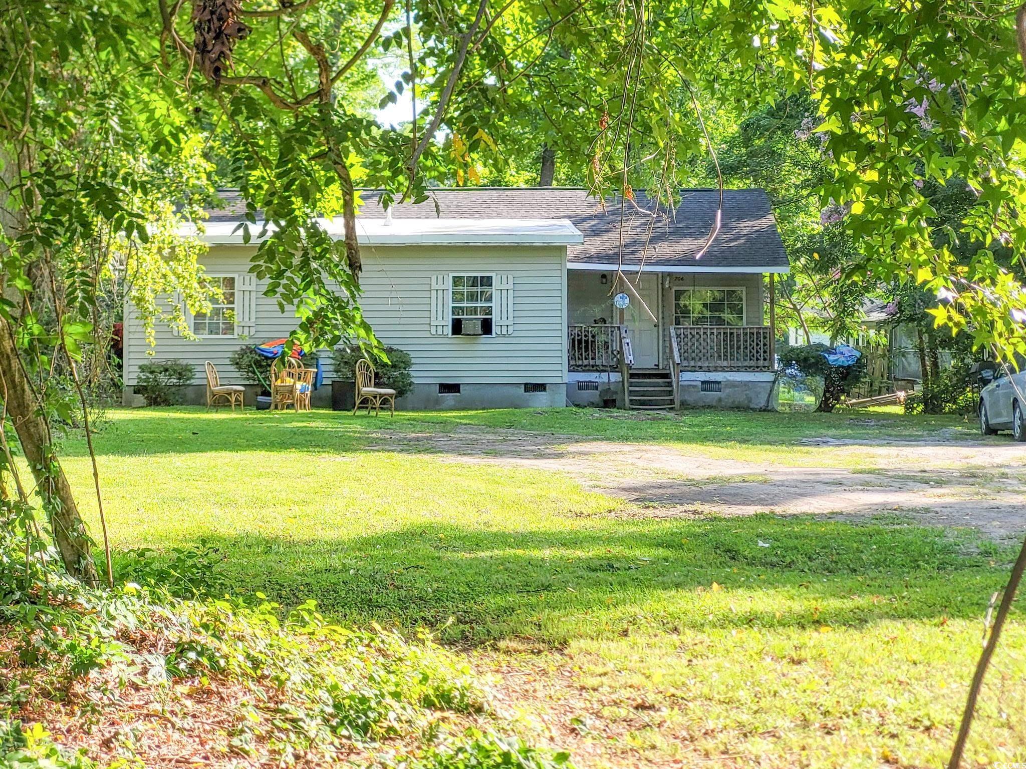 Rear view of house with covered porch, a lawn, and