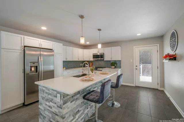 a kitchen with stainless steel appliances granite countertop a sink a stove a refrigerator and island