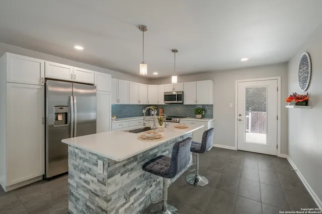 a kitchen with stainless steel appliances granite countertop a sink a refrigerator and a stove