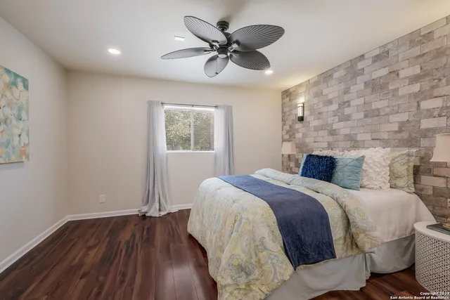 a bedroom with a bed and a ceiling fan with wooden floor