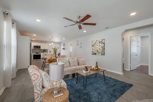 a living room with furniture kitchen view and a chandelier